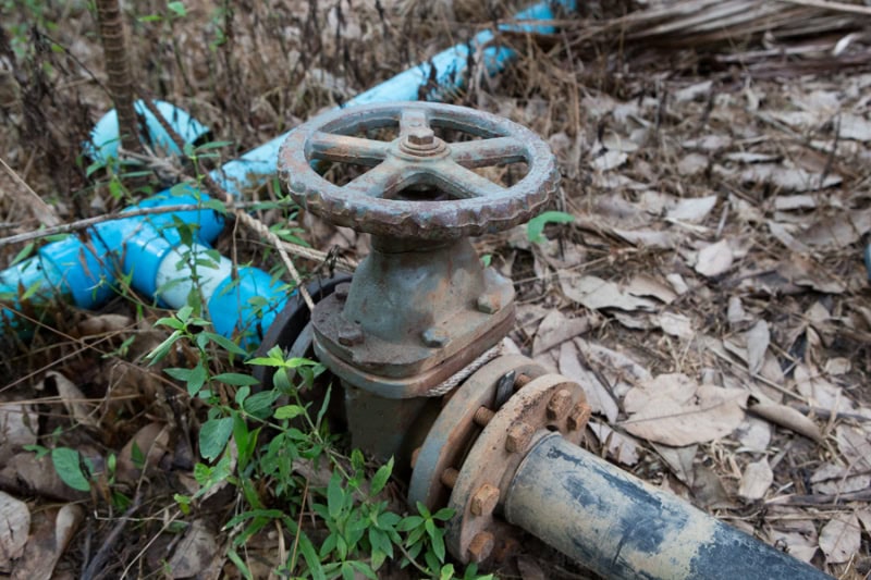 Old, rusty metal gate valve installed on a water or sewer pipeline.